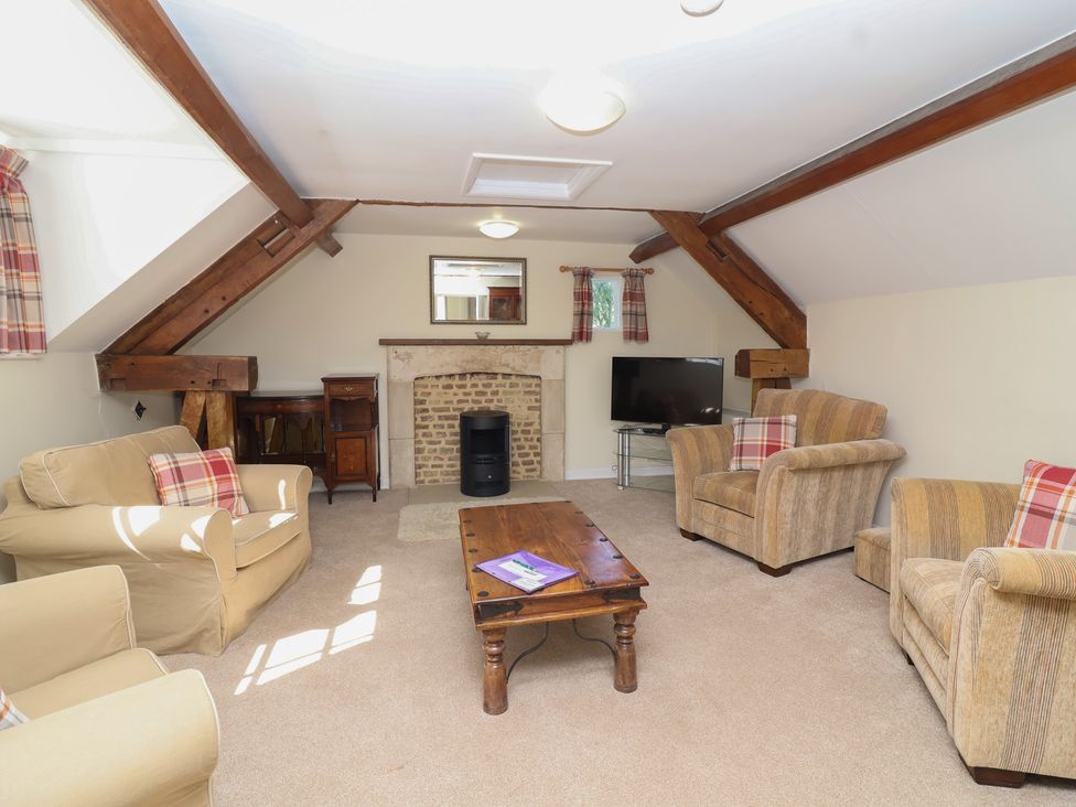 A living room with a sofa, armchairs, and a television at The Old Stables in Gloucester