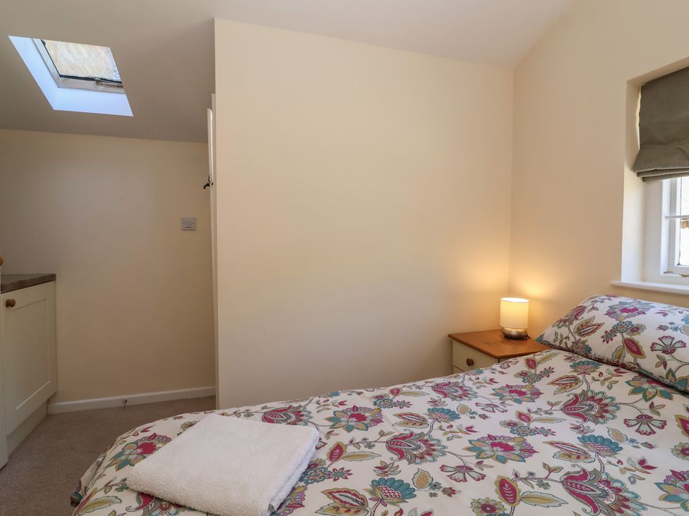 A bedroom with a bed and a lamp on a nightstand at The Old Stables in Gloucester
