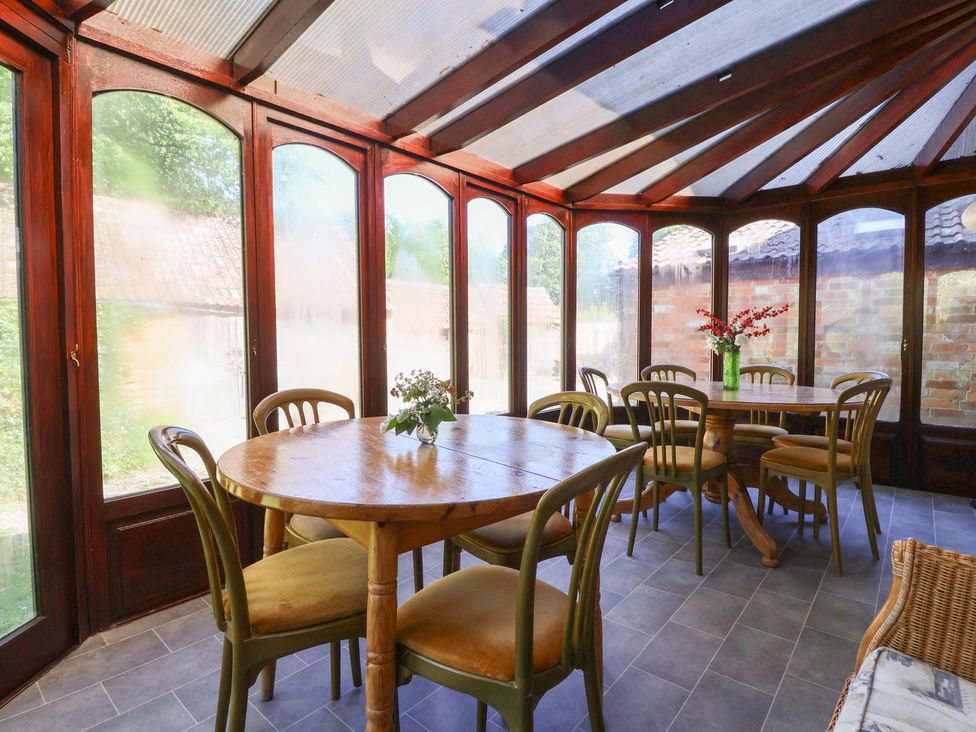 A conservatory with a wooden table and chairs at The Old Stables in Gloucester