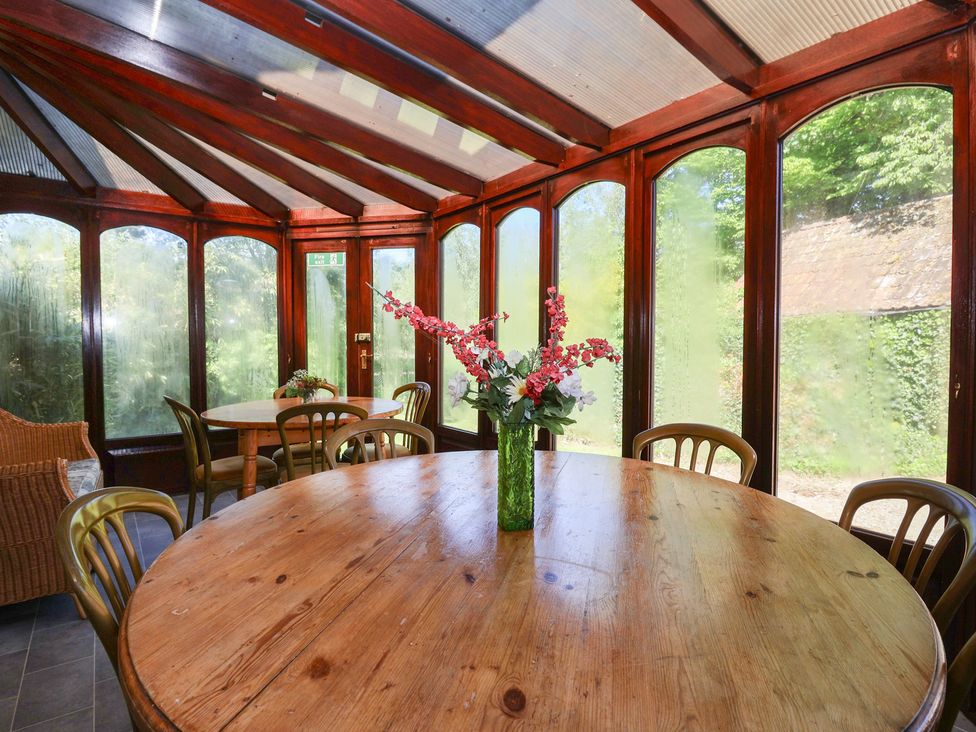 A conservatory with a round table and chairs at The Old Stables in Gloucester