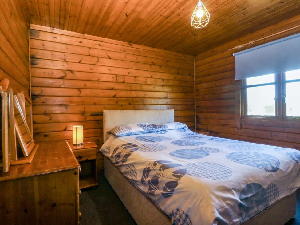 A bedroom with a bed and bedside table at Lodge 5 - Bron Eifion in Criccieth