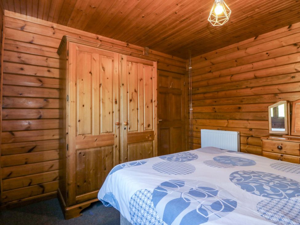 A bedroom with a bed and wardrobe at Lodge 5 - Bron Eifion, Criccieth