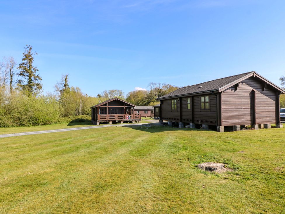 Two cabins surrounded by grass and trees at Lodge 5 - Bron Eifion, Criccieth