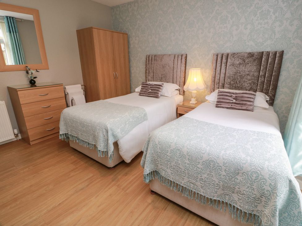 A bedroom with two beds and a wardrobe at 1 St. Catherines Cottages in Perth