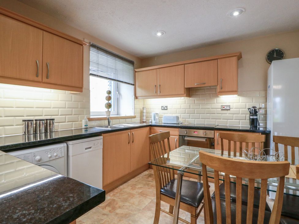 A kitchen with cabinets, appliances, and a dining table at 2 St. Catherines Cottages Perth