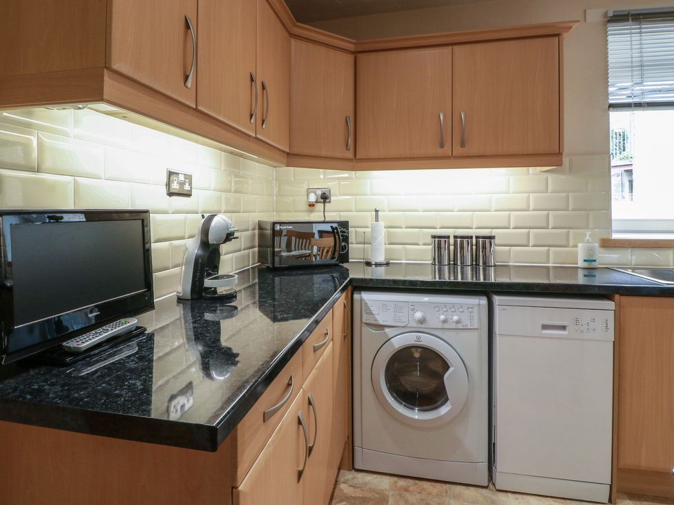 A kitchen with appliances including a washing machine and dishwasher at 2 St. Catherines Cottages in Perth