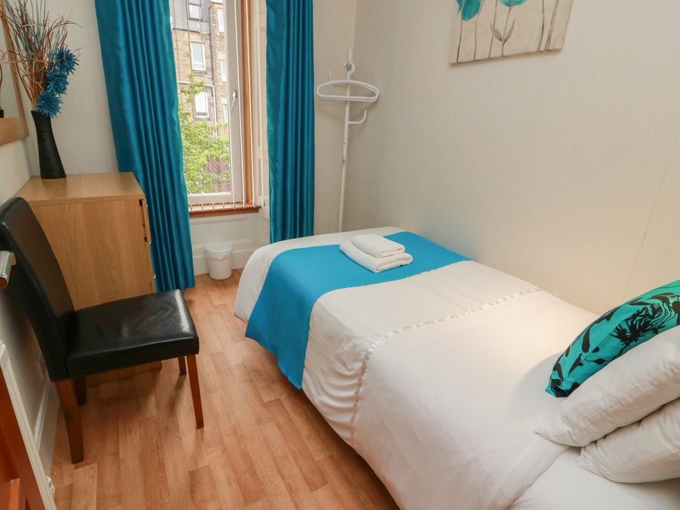 A bedroom with a single bed and a chair at 2 St. Catherines Cottages in Perth