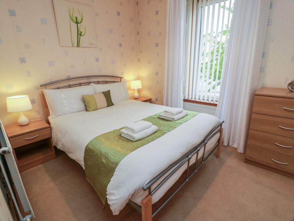 A bedroom with a bed and nightstand at 2 St. Catherines Cottages, Perth
