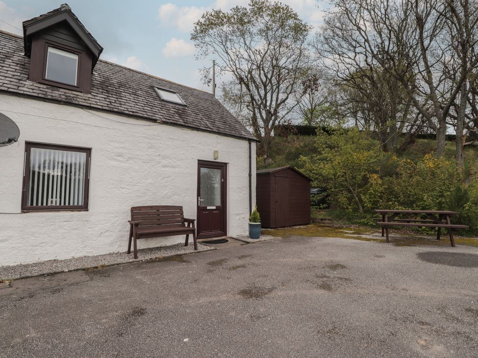An outdoor area with a house, bench, and shed at 3 Bruaich Cottages near Strathpeffer