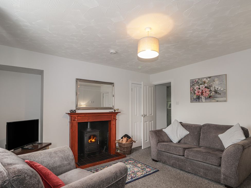 A living room with a fireplace and television at 3 Bruaich Cottages near Strathpeffer
