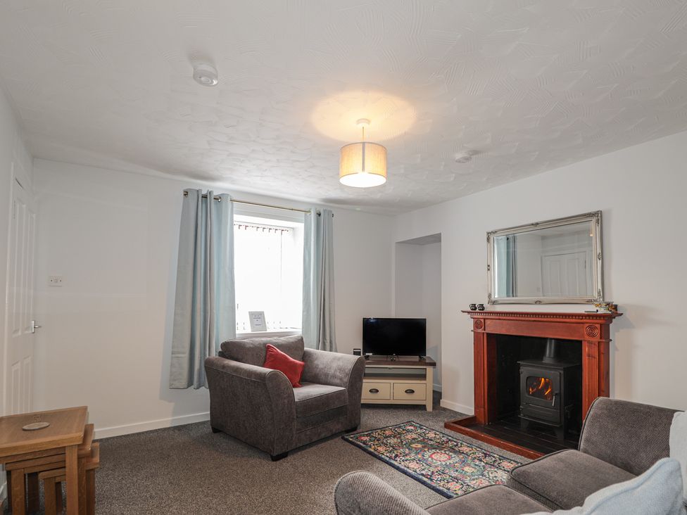 A living room with a sofa and television at 3 Bruaich Cottages near Strathpeffer
