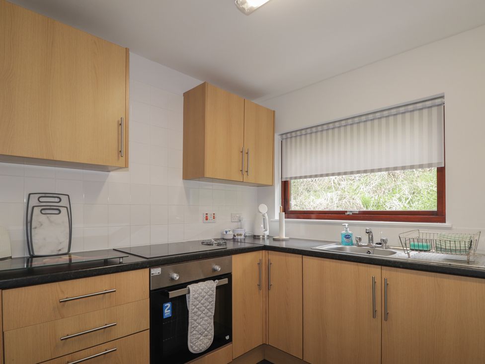 A kitchen with wooden cabinets and a countertop at 3 Bruaich Cottages near Strathpeffer
