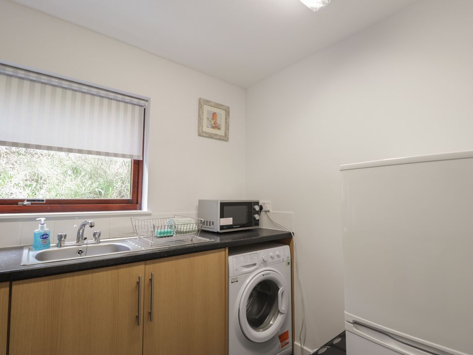 A utility room with a sink and washing machine at 3 Bruaich Cottages near Strathpeffer