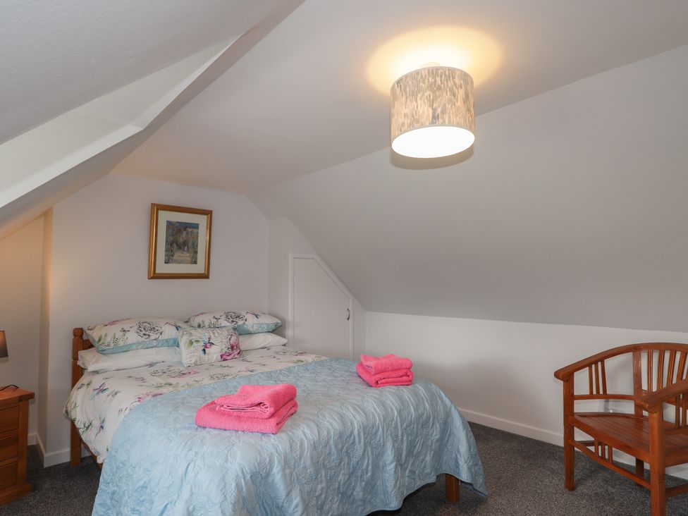 A bedroom with a bed and chair at 3 Bruaich Cottages near Strathpeffer