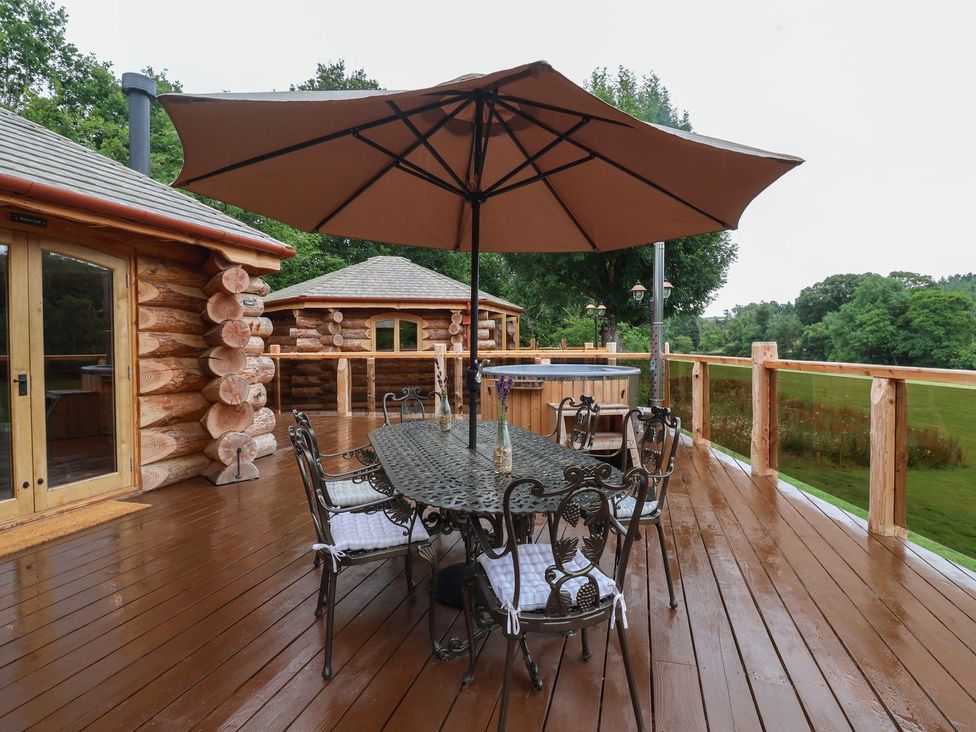 A deck with a table and chairs under an umbrella at Copper Suite in Chulmleigh