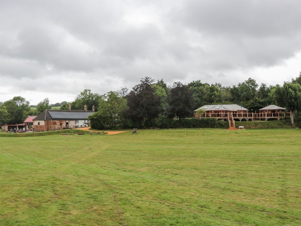 A grassy area with trees and buildings at Copper Suite Chulmleigh