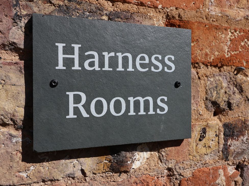 A sign that reads 'Harness Rooms' affixed to a brick wall at Harness Rooms Gloucester