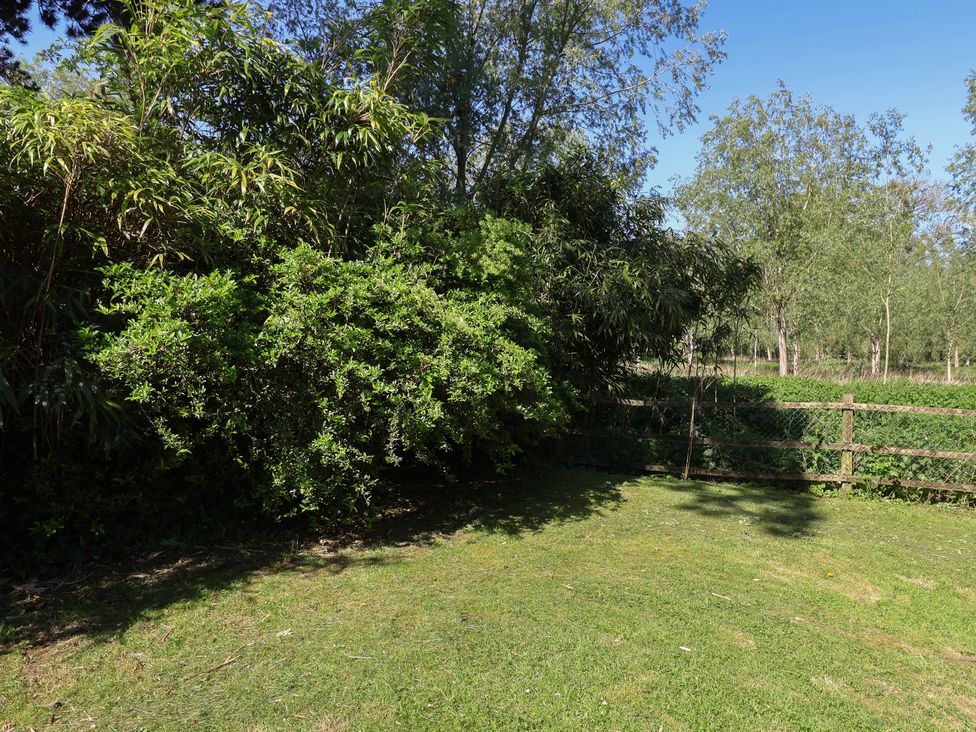 A garden with grass and bushes at Harness Rooms in Gloucester
