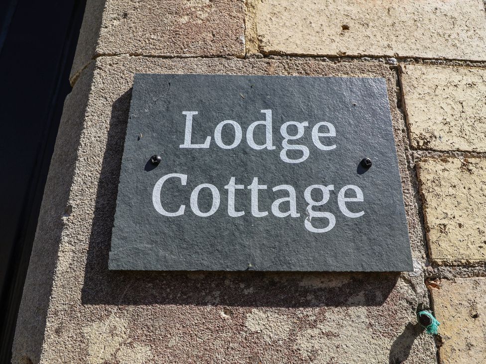 A sign that reads Lodge Cottage on a stone wall at The Lodge in Gloucester