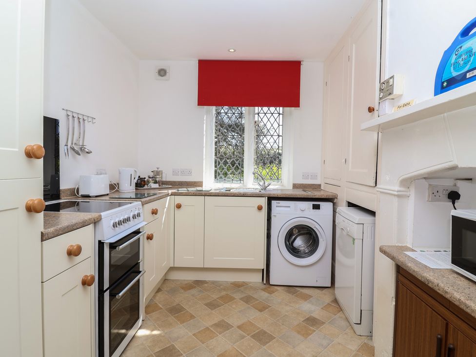 A kitchen with cabinets, stove, washing machine, and window at The Lodge in Gloucester