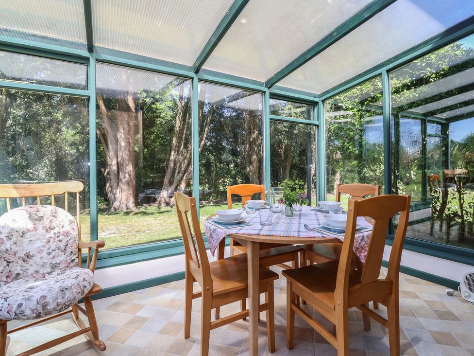 A conservatory with a dining table and chairs at The Lodge in Gloucester
