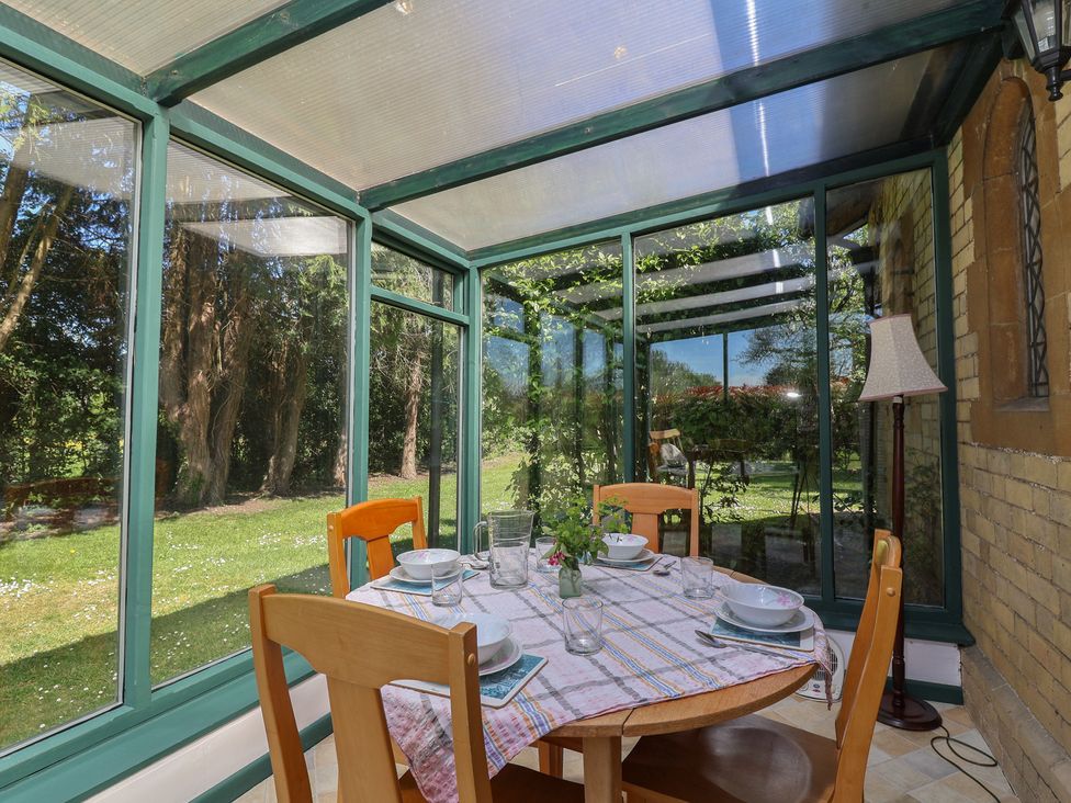 A conservatory with a dining table and chairs at The Lodge in Gloucester