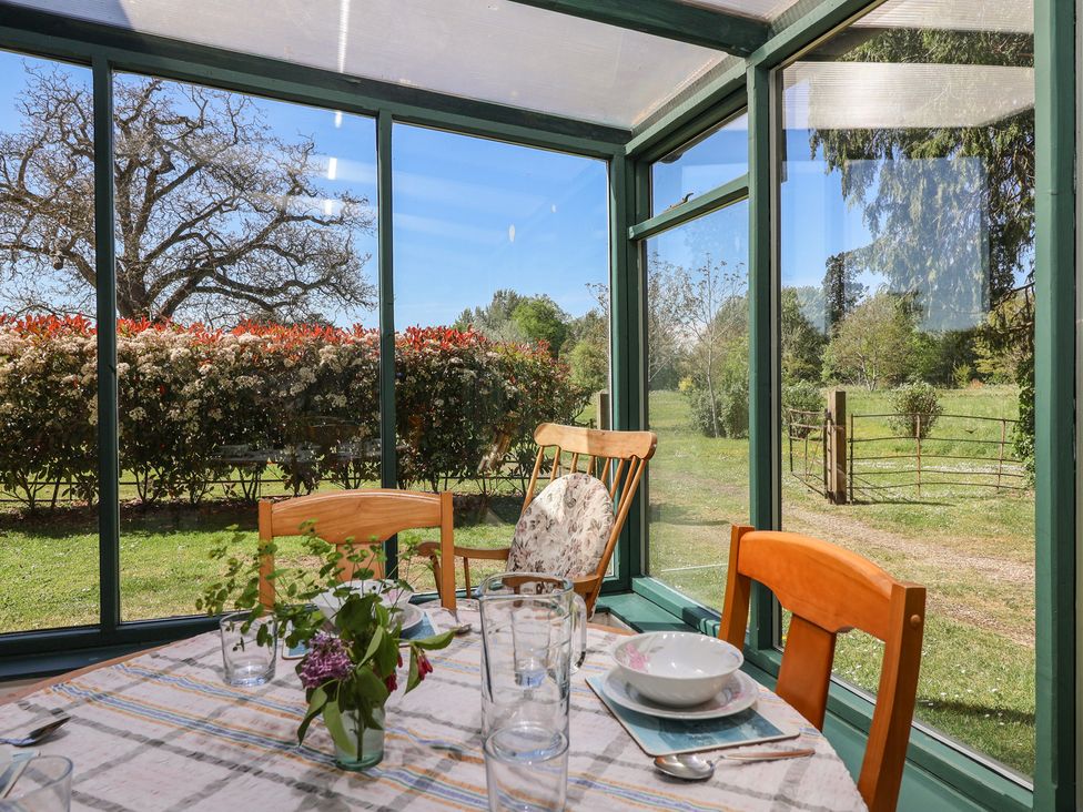 A conservatory with a table set for dining at The Lodge in Gloucester