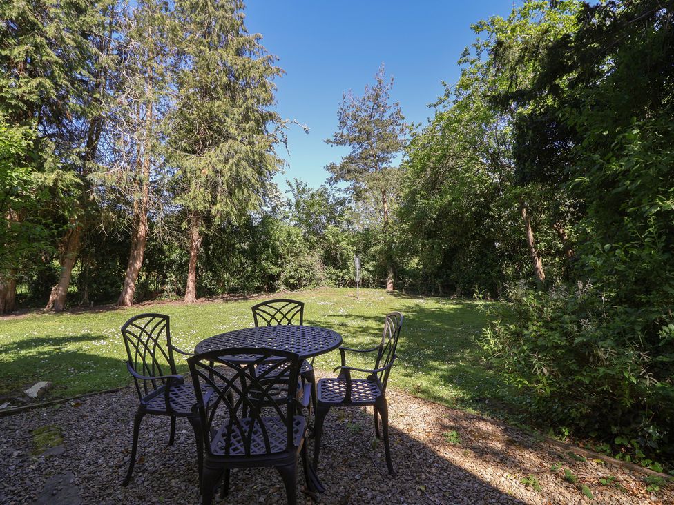 A garden with a table and chairs surrounded by trees at The Lodge in Gloucester