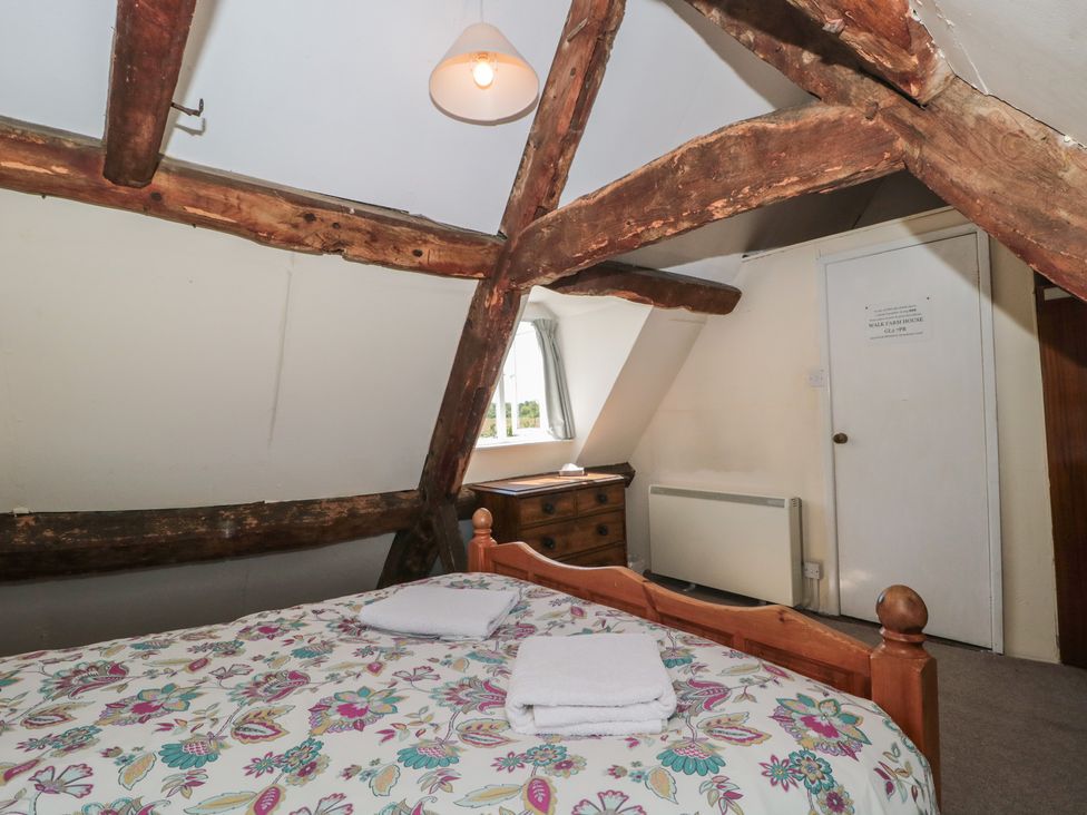 A bedroom with a bed, dresser, and window at Walk Farmhouse in Gloucester
