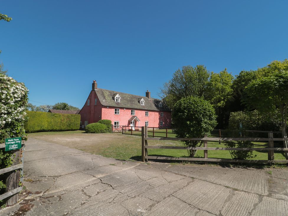 A pink house with fence and trees at Walk Farmhouse in Gloucester