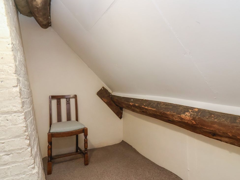 An attic space with a chair and wooden beams at Walk House in Gloucester