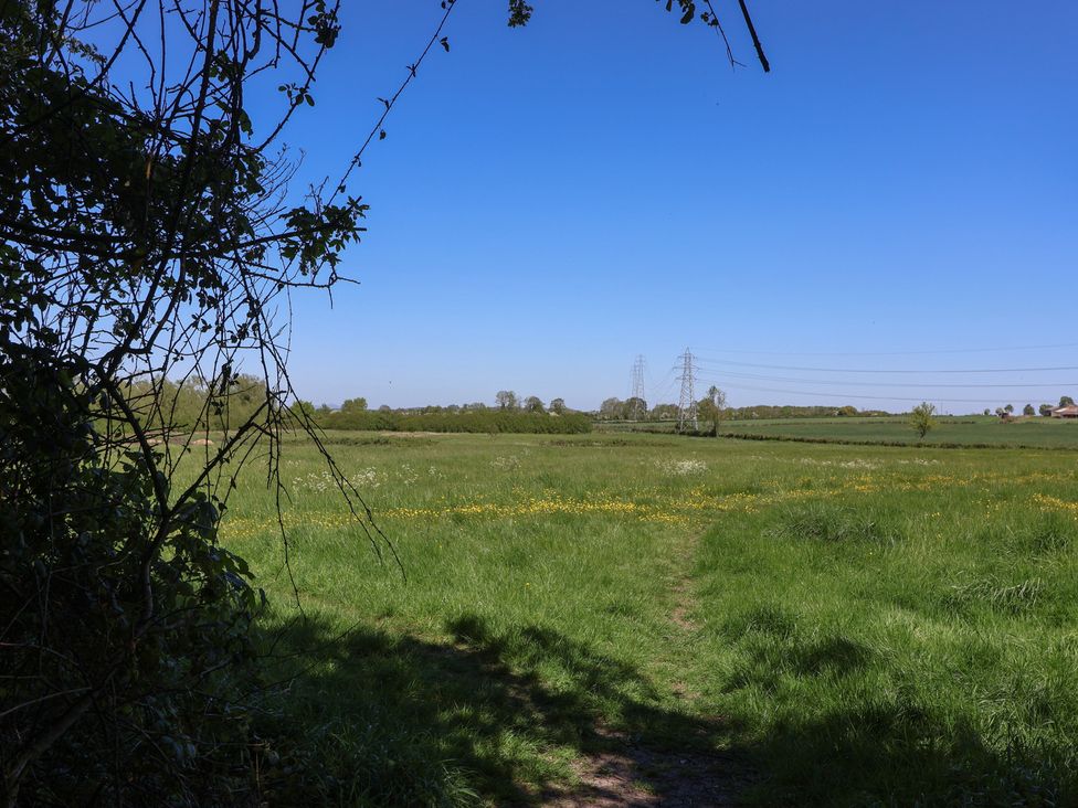 A grassy field with a pathway and electricity pylons at Walk House, Gloucester