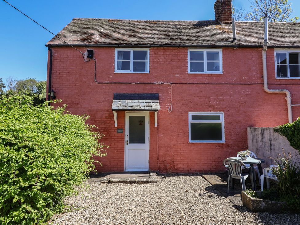 A house with a door and windows and outdoor seating at Walk Farm Cottage in Gloucester