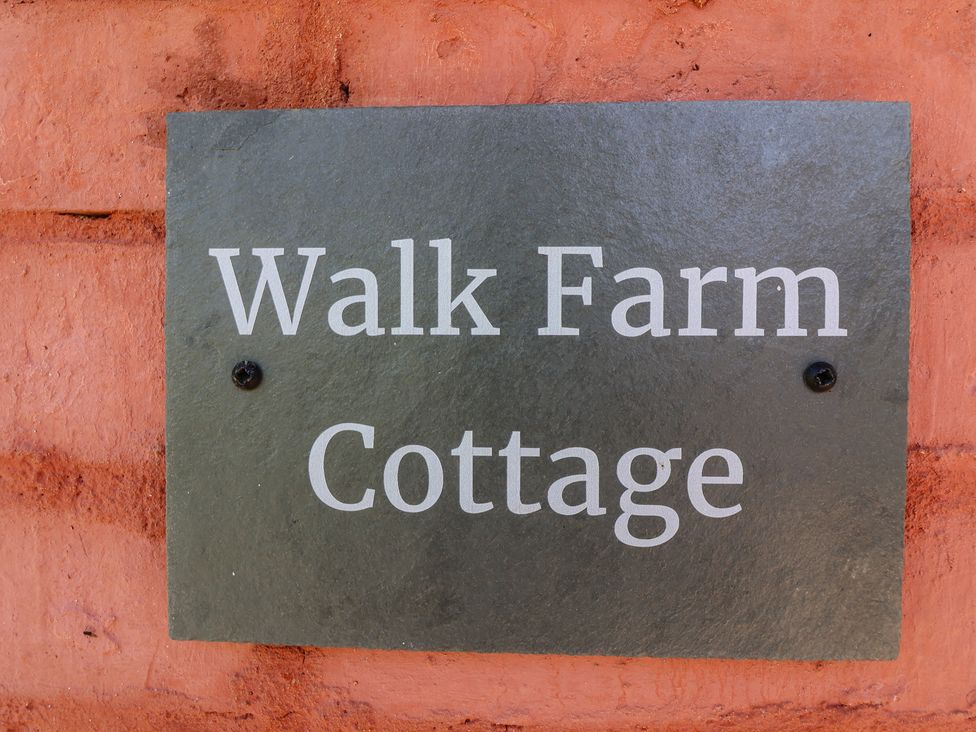 A sign displaying 'Walk Farm Cottage' on a brick wall at Walk Farm Cottage in Gloucester
