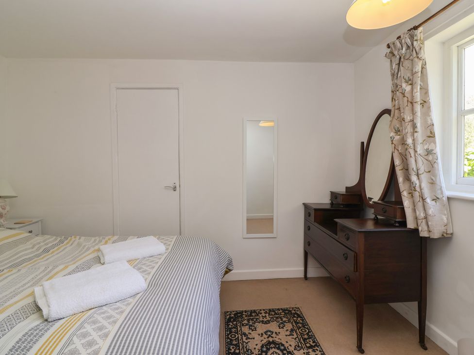 A bedroom with a bed and dressing table at Walk Farm Cottage in Gloucester