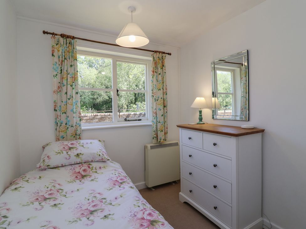 A bedroom with a single bed and a dresser at Walk Farm Cottage in Gloucester