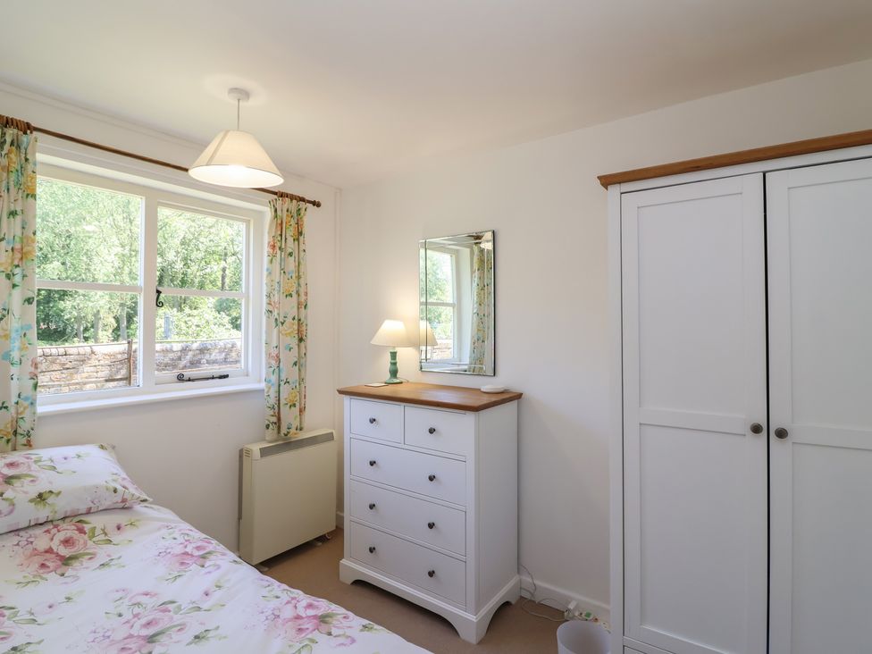 A bedroom with a bed, window, chest of drawers and wardrobe at Walk Farm Cottage in Gloucester