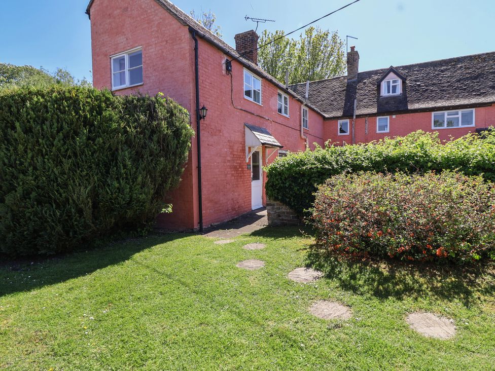 An outdoor view of a pink house with greenery at Walk Farm Cottage in Gloucester