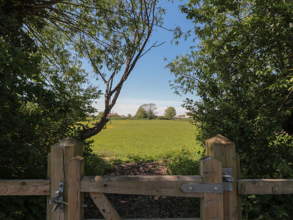 A view of a grass field from a wooden gate at Walk Farm Cottage in Gloucester