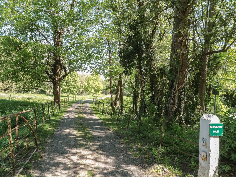 A path lined with trees and a sign at Whittminster House in Gloucester