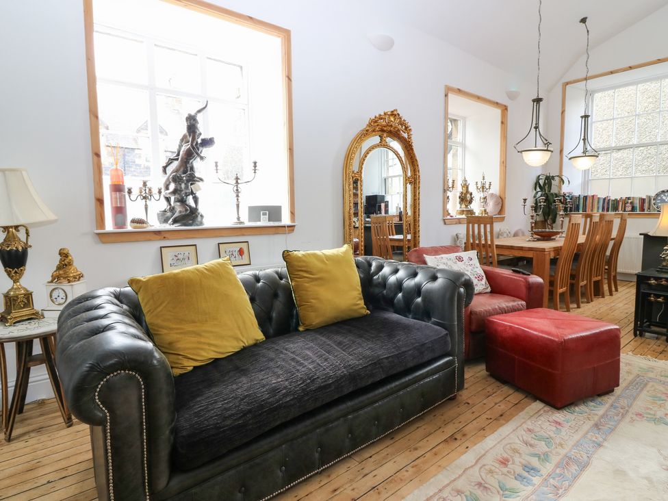 A living room with a sofa, dining table, and decorative items at The Old School in Peebles