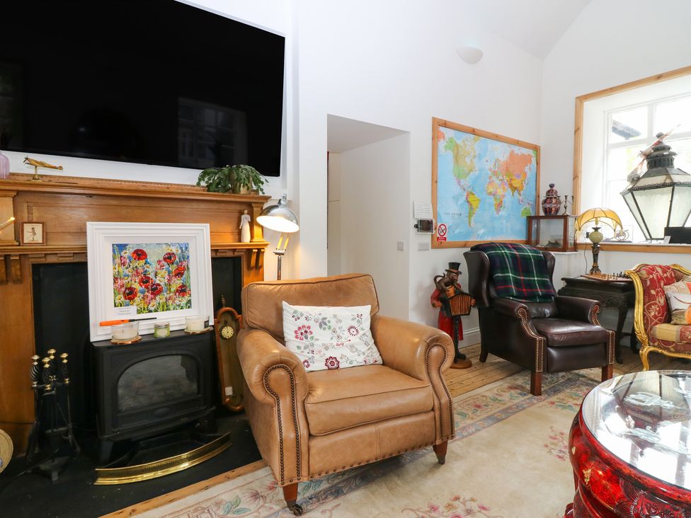 A living room with a television, sofa and paintings at The Old School in Peebles