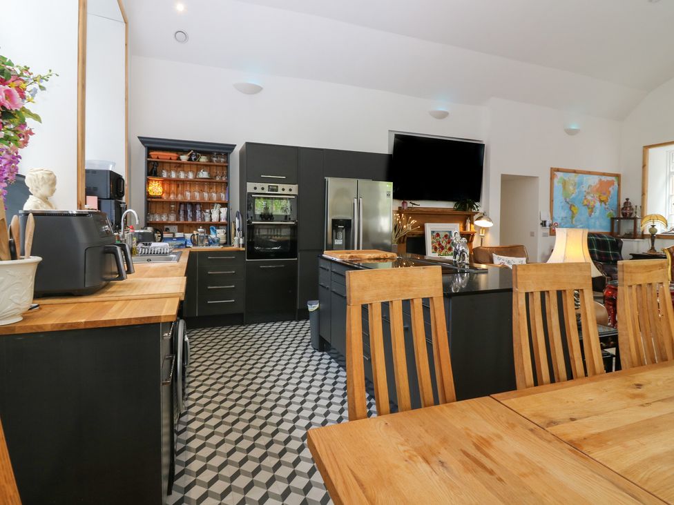 A kitchen with dining table and refrigerator at The Old School in Peebles
