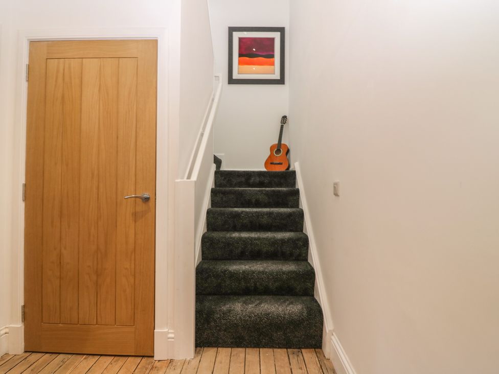 A staircase leading to a door with a guitar on the steps at The Old School in Peebles