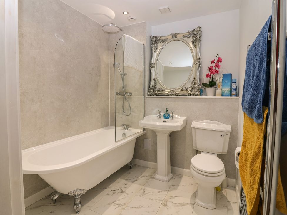 A bathroom with a bathtub, toilet, sink, and mirror at The Old School in Peebles
