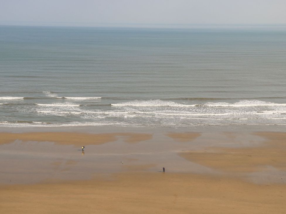 A beach scene with two people on the sand
