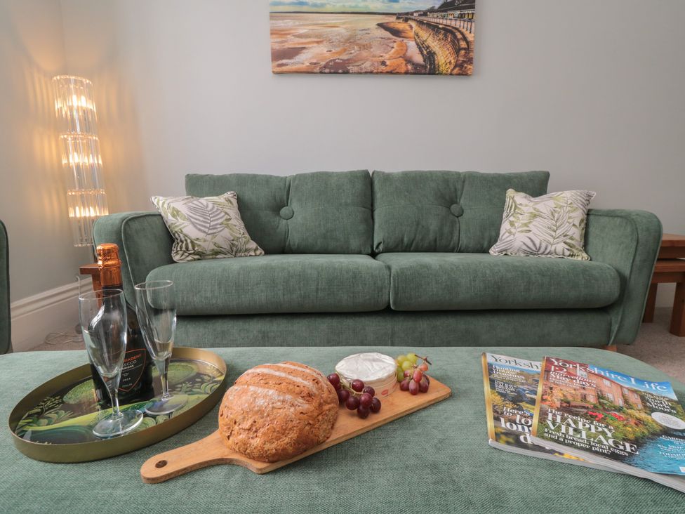 A living room with a green sofa and snacks at 5 Station Avenue