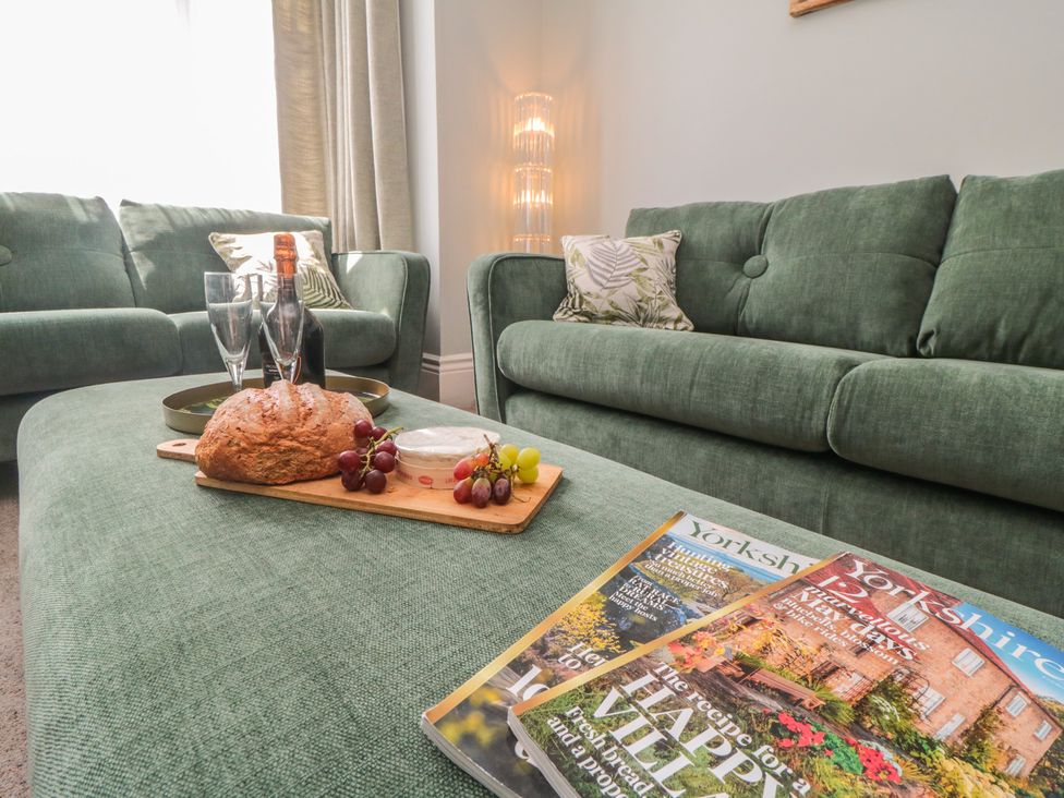 A living room with a sofa and magazines at 5 Station Avenue