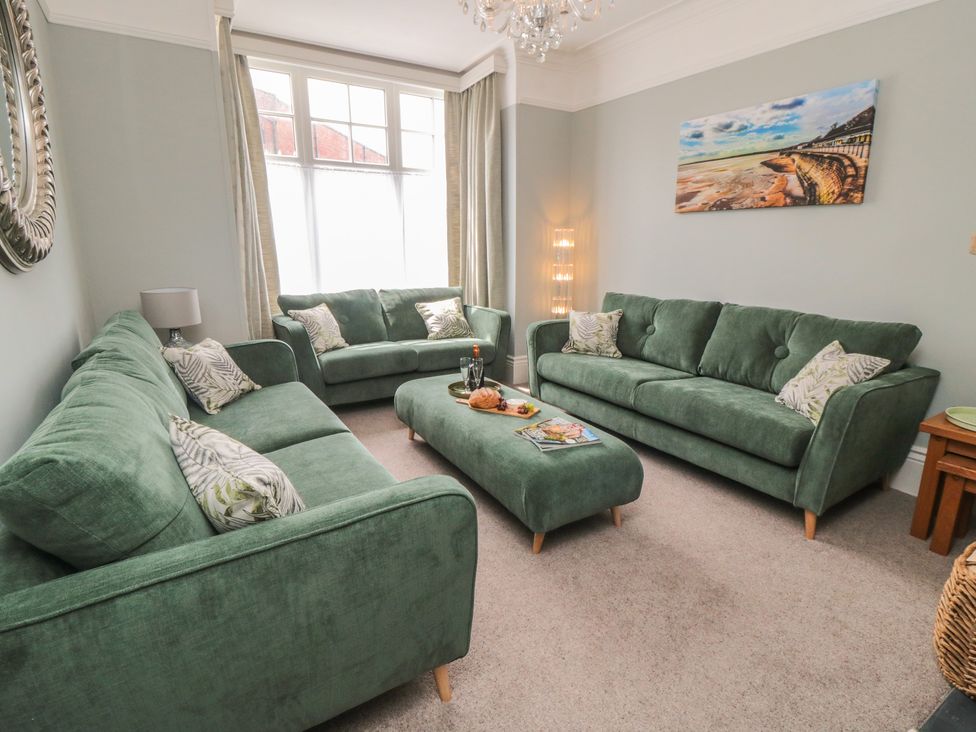A living room with green sofas and coffee table at 5 Station Avenue