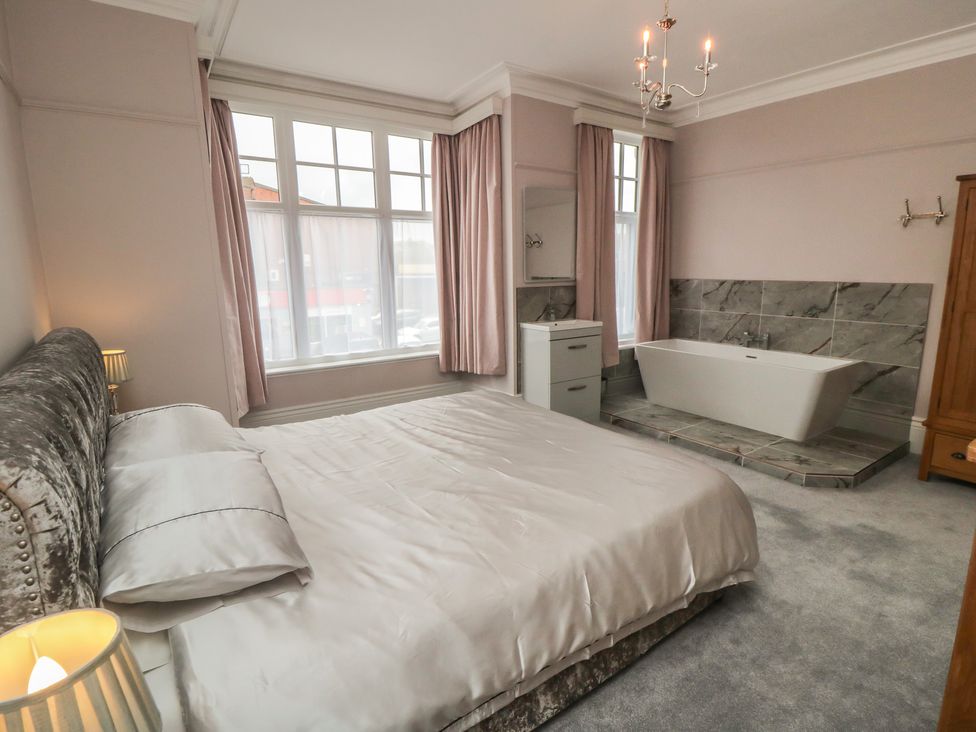 A bedroom with a bed, lamp, and bathtub at 5 Station Avenue